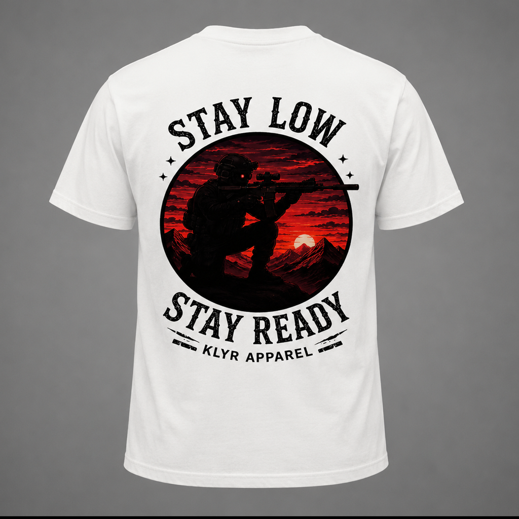 Back ghost mannequin view of the white KLYR Stay Low Stay Ready Tee featuring a tactical operator silhouette against a red sunset mountain landscape.