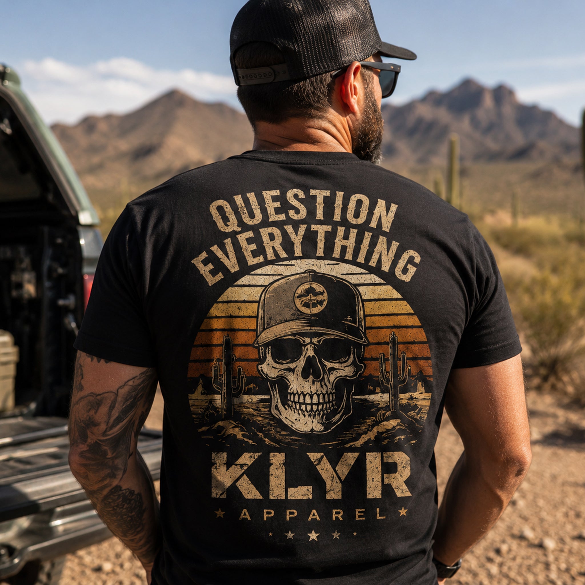 Person wearing the black KLYR Question Everything Tee showcasing the large skull and desert sunset back graphic with "Question Everything" text.