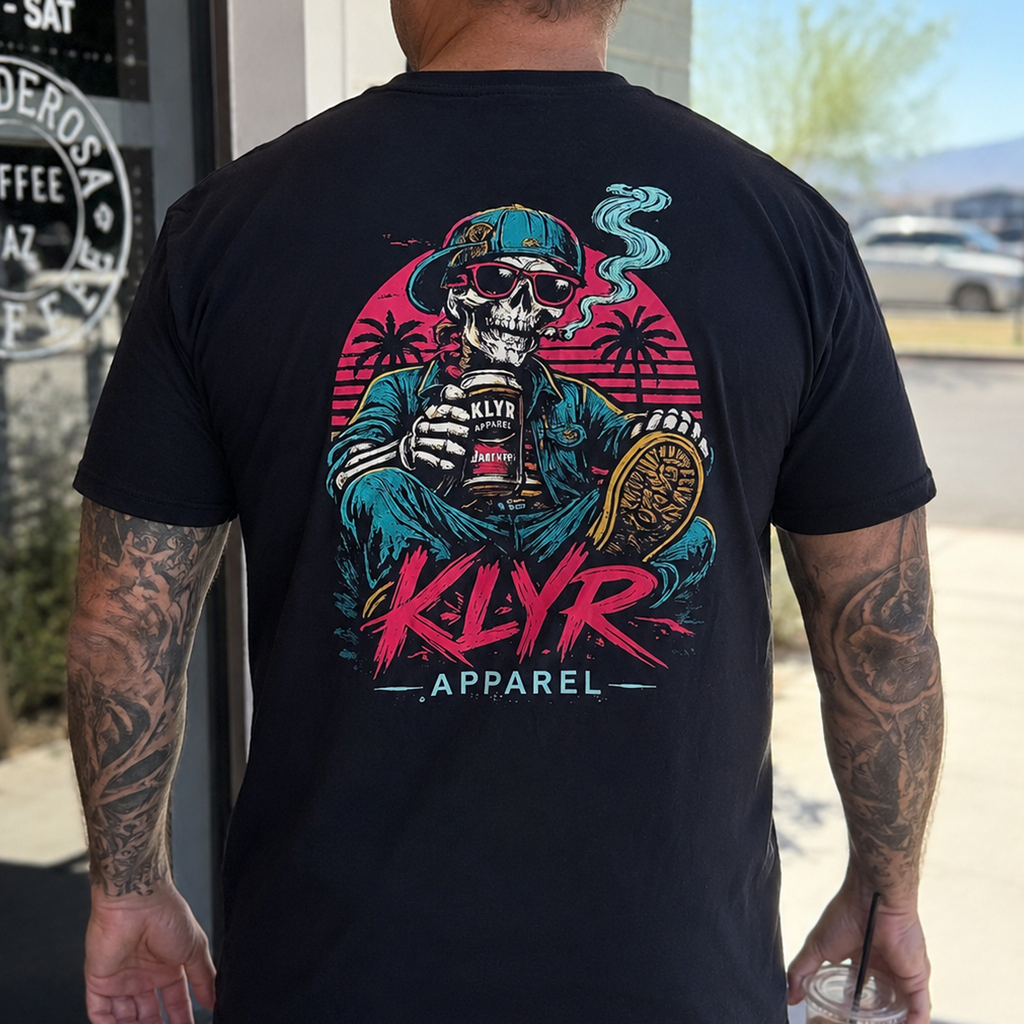Person wearing the black KLYR Apparel After Hours Tee showing the colorful retro skeleton back graphic outside a coffee shop.