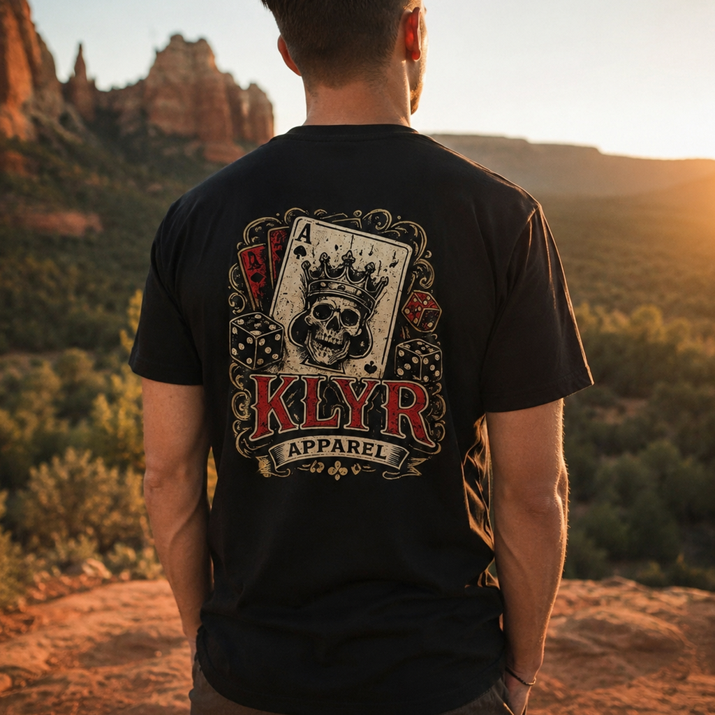 Person wearing the black KLYR Aces Tee outdoors showcasing the skull king playing card back graphic in a desert landscape.
