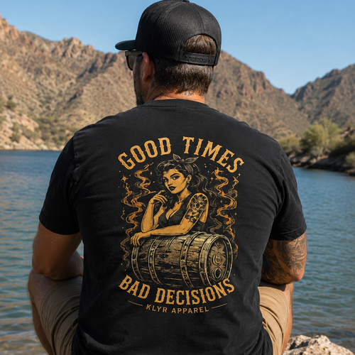 Rear lifestyle view of the black KLYR Good Times Bad Decisions Tee showcasing the vintage pin-up and whiskey barrel back graphic beside a desert lake.