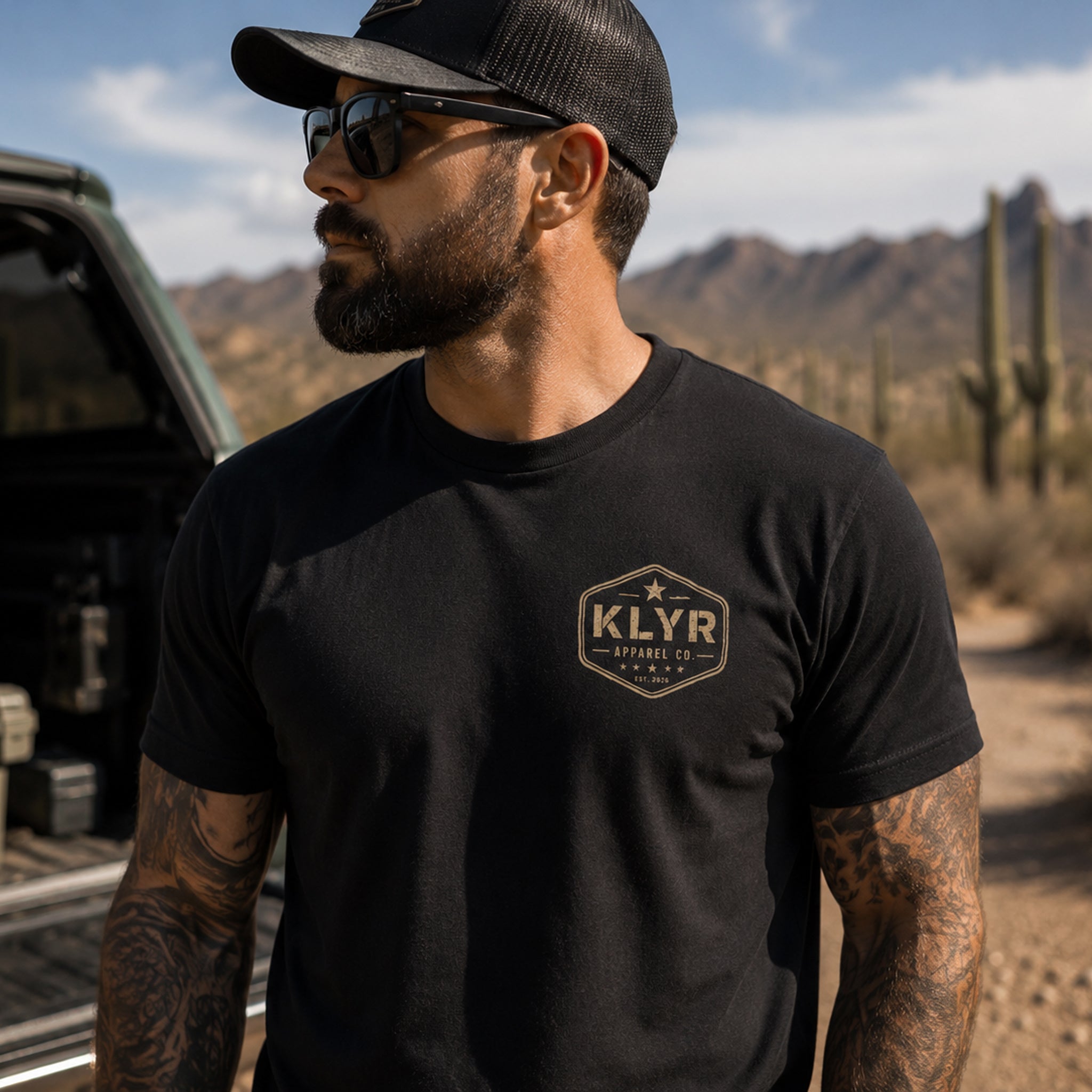 Front lifestyle view of the black KLYR Question Everything Tee featuring the vintage KLYR Apparel Co. chest logo in a desert setting.
