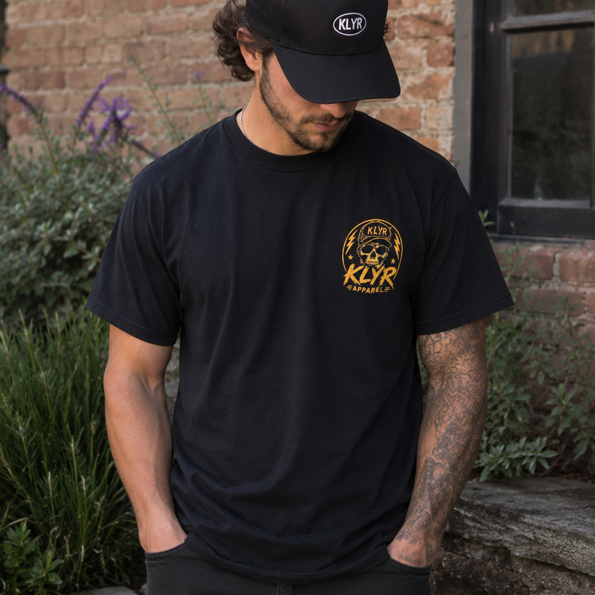 Lifestyle front view of a model wearing the black KLYR Homies Tee with a small yellow chest logo.
