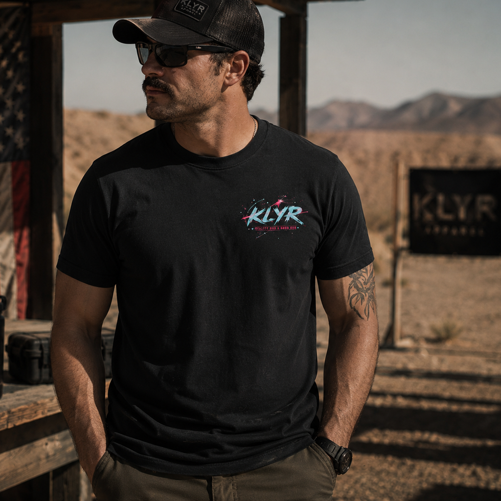 Front lifestyle view of the black KLYR Reality Had a Good Run Tee featuring the retro neon chest logo in an outdoor desert setting.