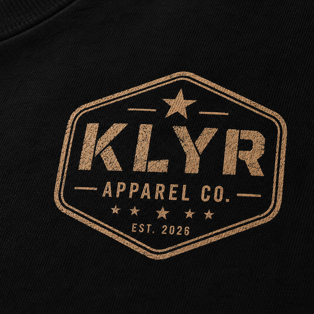 Detailed close-up of the vintage KLYR Apparel Co. chest logo printed on the black KLYR Question Everything Tee.