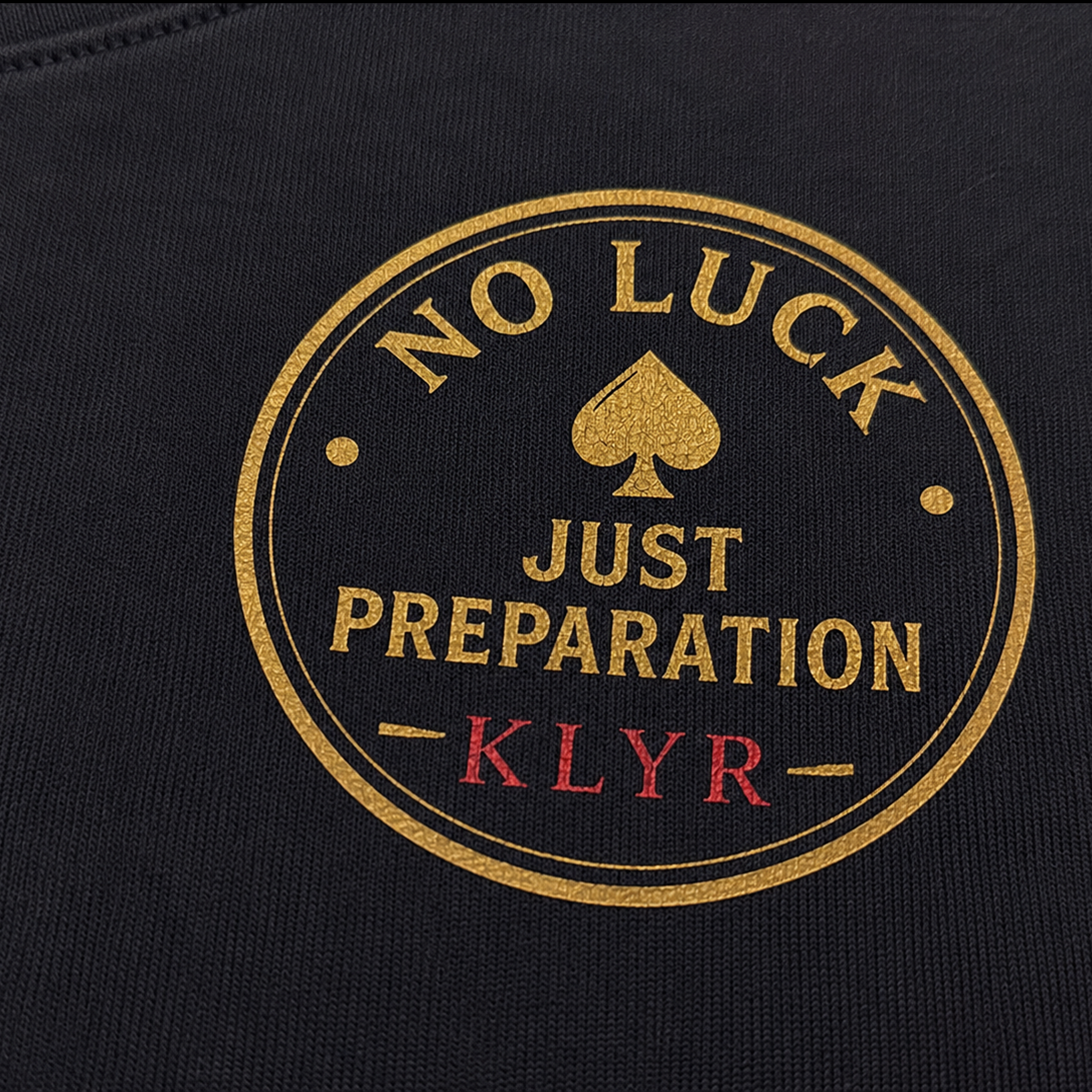 Detailed close-up of the No Luck Just Preparation chest logo printed on the black KLYR Aces Tee.