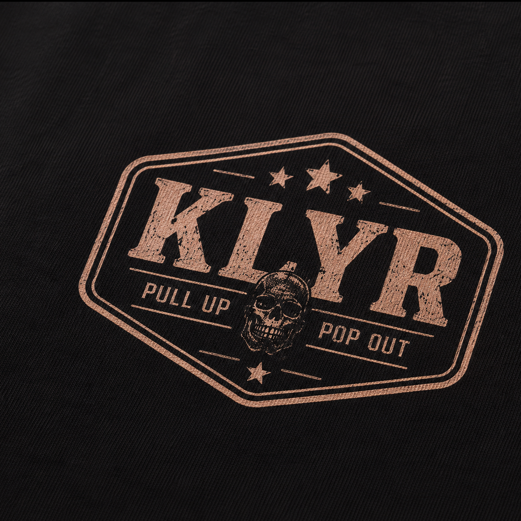 Detailed close-up of the Pull Up Pop Out vintage tactical chest logo printed on the black KLYR Pull Up Pop Out Tee.