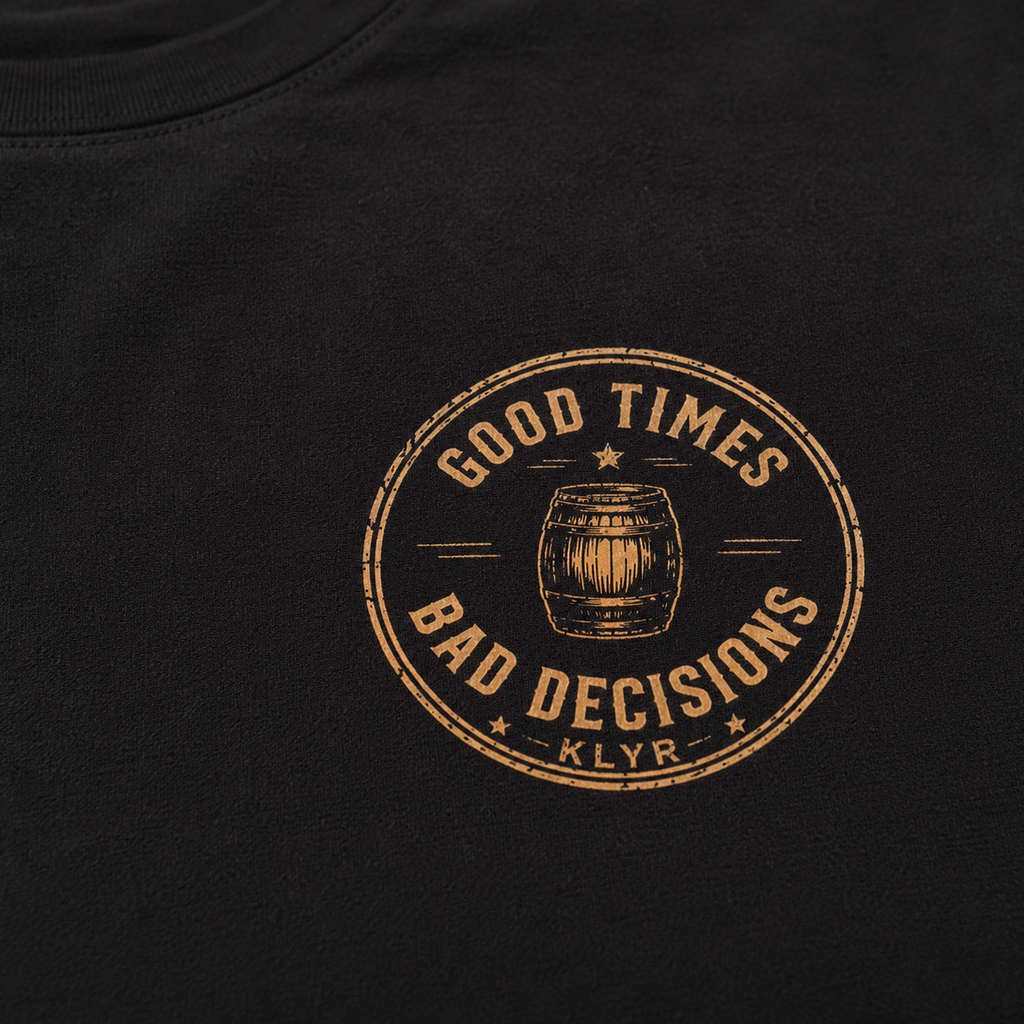 Detailed close-up of the Good Times Bad Decisions chest logo featuring a vintage whiskey barrel emblem on the black KLYR tee.