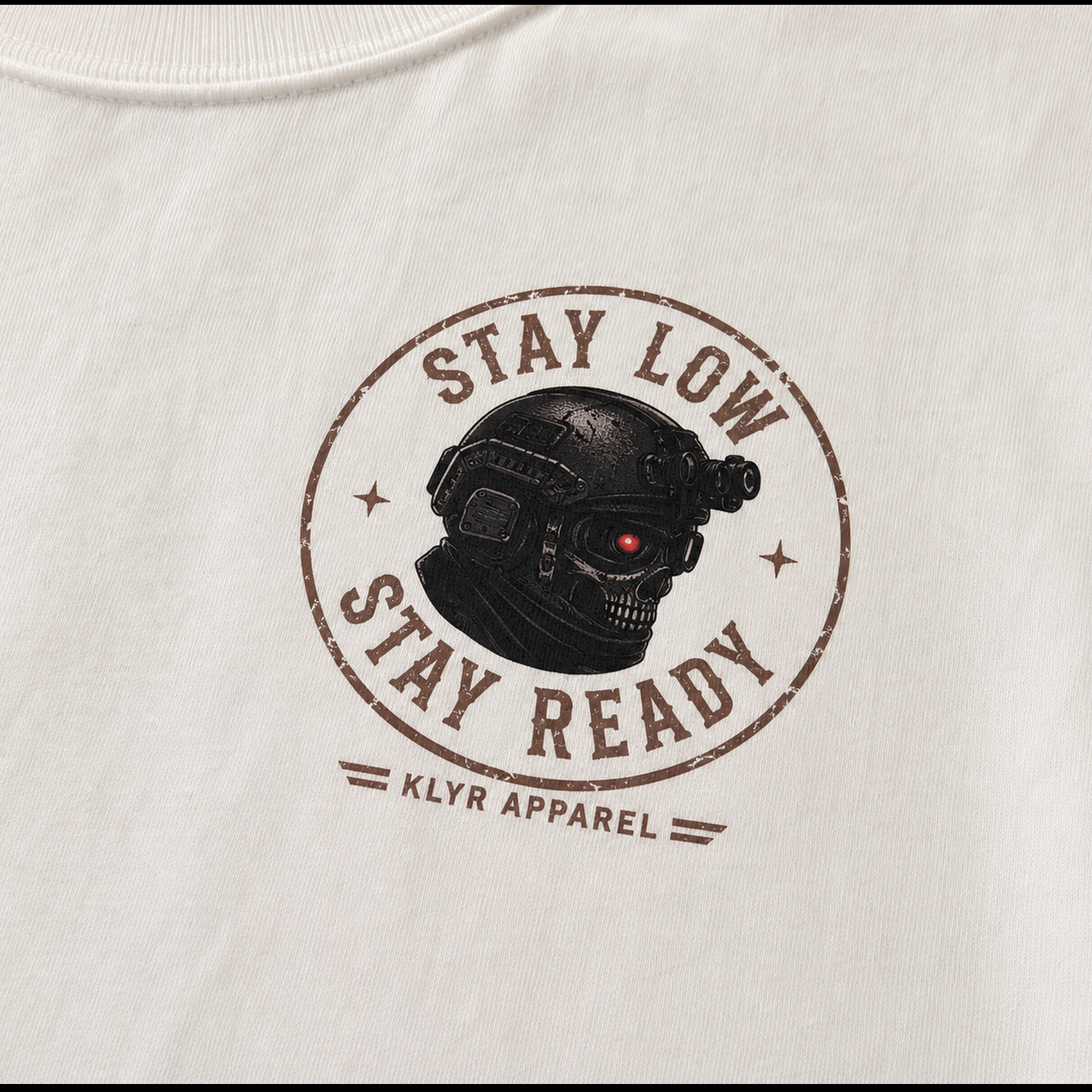Detailed close-up of the Stay Low Stay Ready tactical helmet chest logo printed on the white KLYR Stay Low Stay Ready Tee.