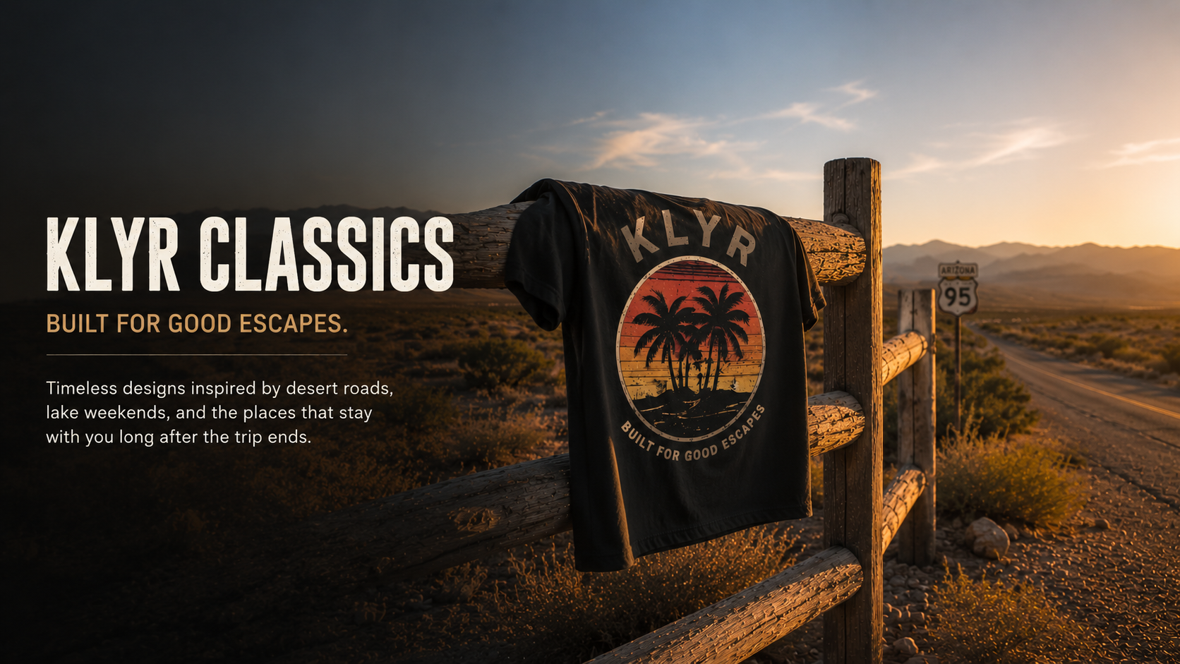 Black KLYR Classics graphic tee hanging on a weathered fence beside Arizona Route 95 at golden hour.