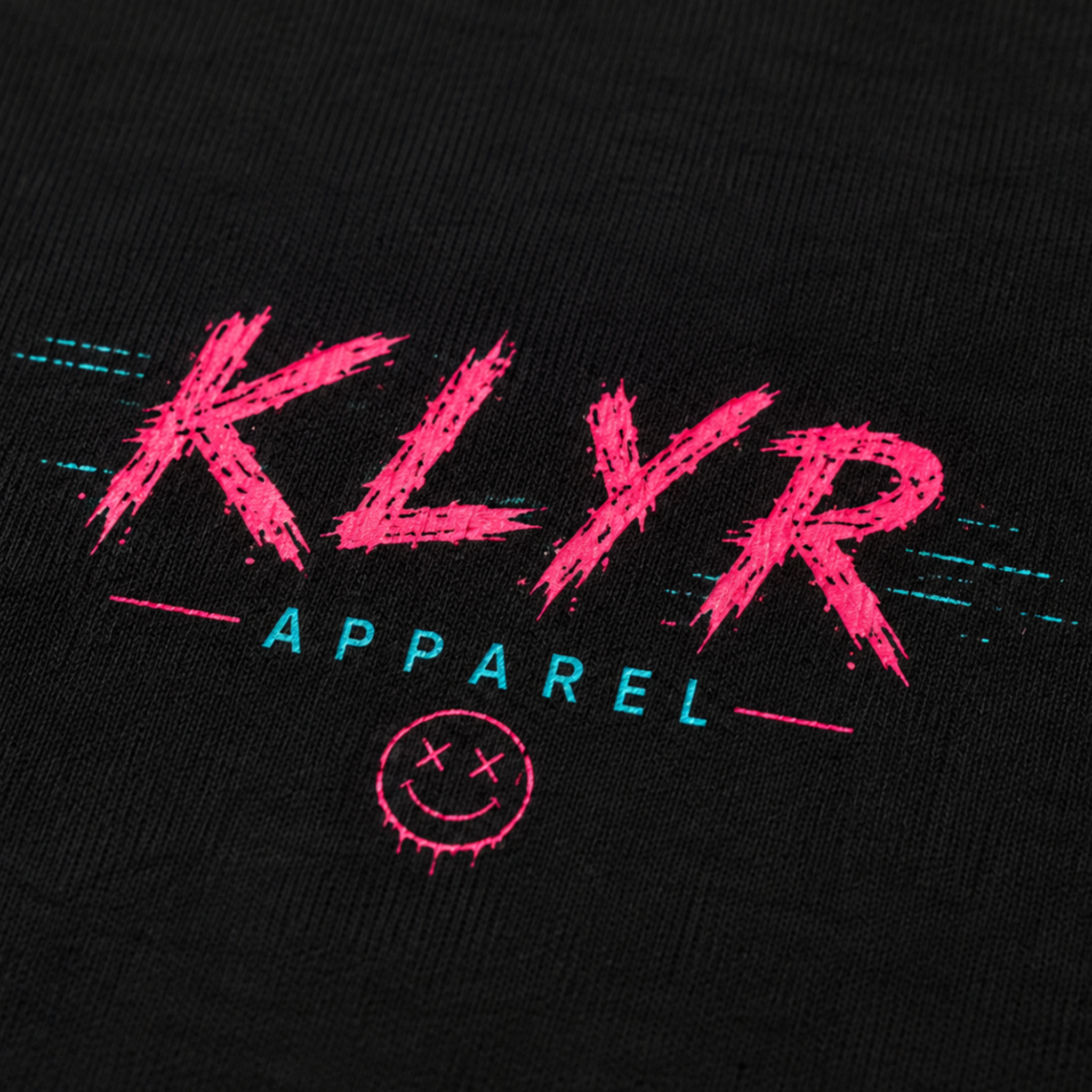 Close-up of the neon pink and cyan KLYR Apparel chest logo on the Reality Glitch Tee.