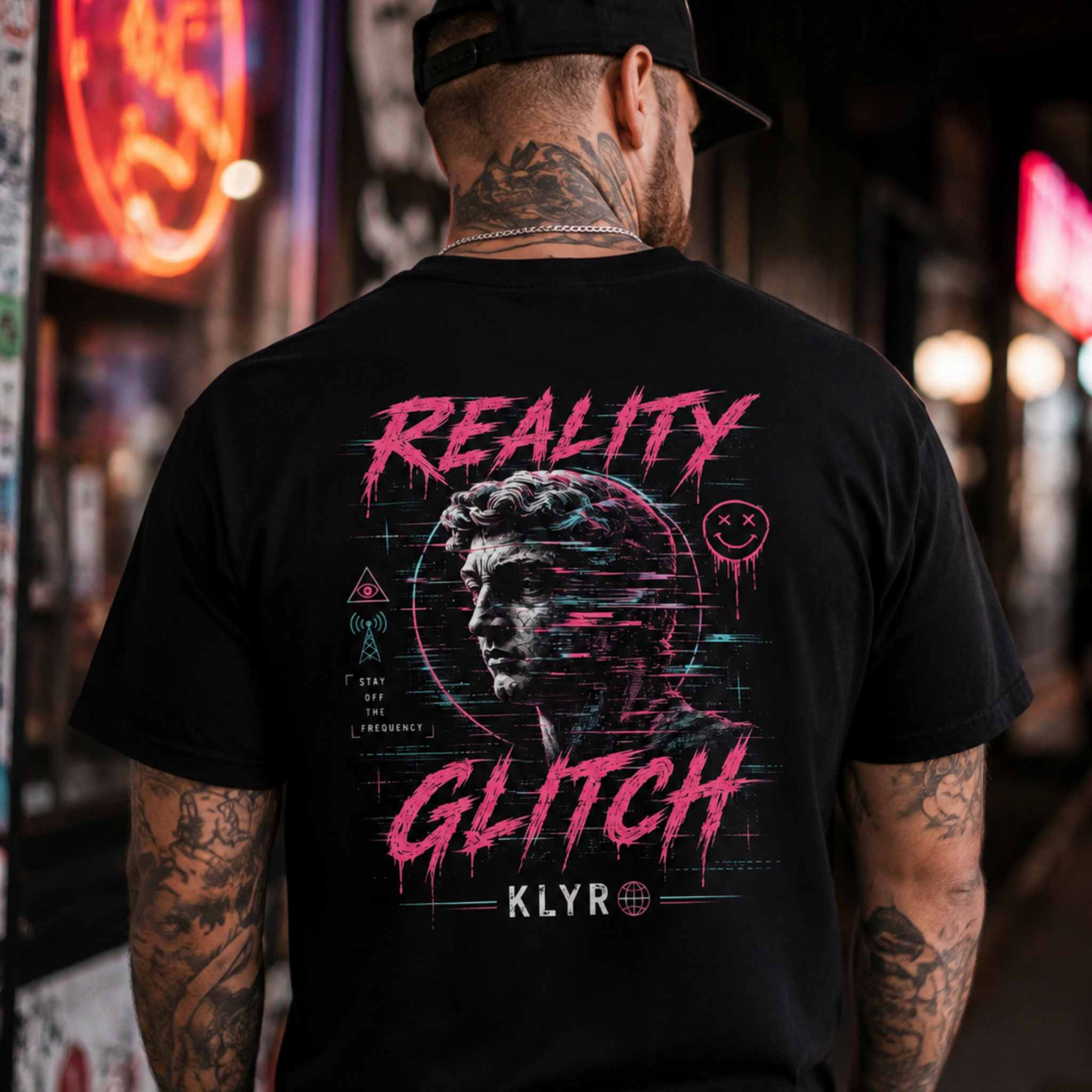 Person wearing the black Reality Glitch Tee in a neon urban setting with the full glitch back graphic visible.