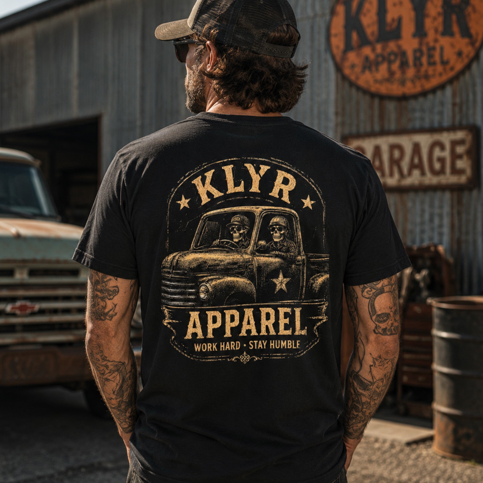 Person wearing the black Work Hard Stay Humble Tee beside a vintage pickup with the full back graphic visible.